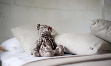 침대에 올라와 있는 곰돌이 인형
